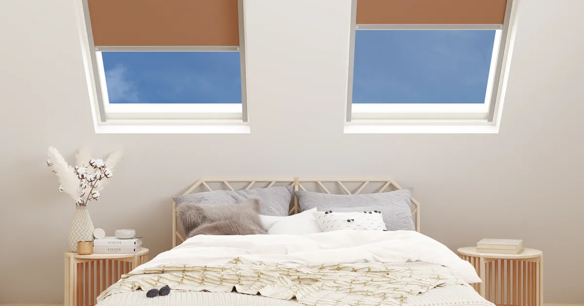 Attic bedroom with two roof windows fitted with Rust Blackout blinds above a double bed